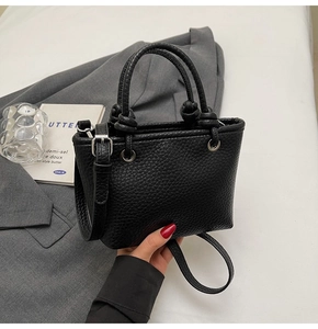 Detail of black lychee grain leather mini tote bag with knotted handles and thin strap