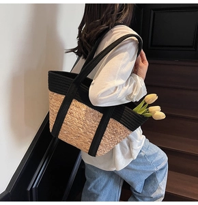 Détail du sac cabas en paille avec sangles tissées noires et texture en fibre naturelle