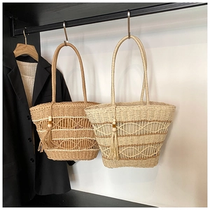 Detailed close-up of handmade bohemian woven straw tote bags with wooden bead tassels