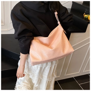 Close-up of the light pink woven texture and soft shoulder strap on a large tote bag