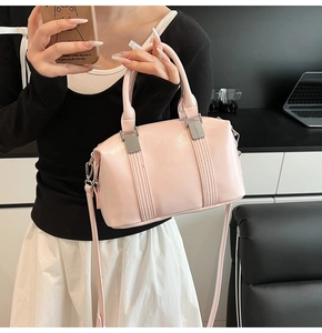 Pink Boston style handbag with silver hardware and dual handles shown with a crossbody strap