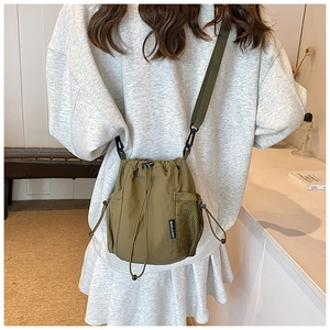Army green nylon bucket bag with drawstring closure and mesh side pocket on model