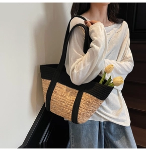 Detail of a large straw tote bag with black fabric trim and decorative yellow tulips