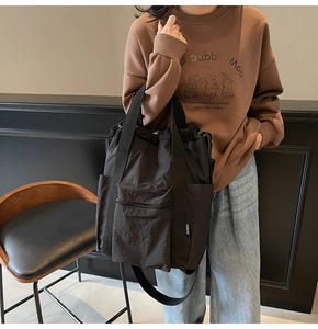 Detail of black multi-functional tote bag with drawstring closure and front zipper pocket