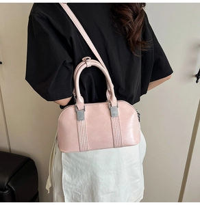 Detailansicht eines Modells mit einer rosa glänzenden Boston-Tasche aus Leder mit Silberteilen