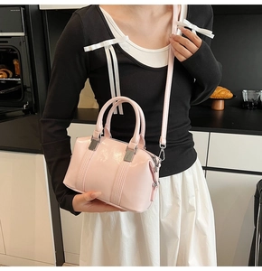 Detail of pink glossy boston bag with adjustable shoulder strap on female model