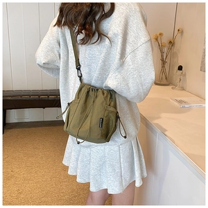 Green nylon bucket bag side mesh pocket and adjustable strap shown on model back