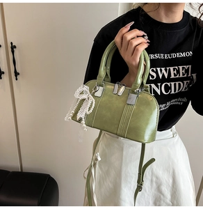 Detail der grünen Boston-Handtasche mit Perlen-Spitzenbogen und Schultergurt