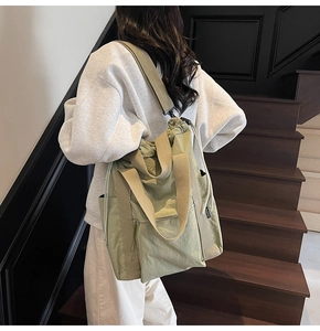Detailed view of wide fabric straps and drawstring closure on olive green nylon tote bag