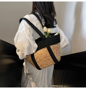 Grand sac cabas en paille avec anses en corde noire porté par un mannequin en robe d'été
