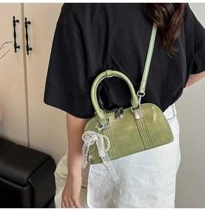 Details der grünen Lackleder-Umhängetasche mit Spitzenbogen und Perlen-Accessoire