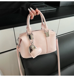 Detail of light pink patent leather mini bowling bag with heart charm and silver chain