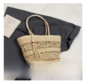 Detail of bohemian hollow-out straw handbag featuring beige woven patterns and fringe tassel