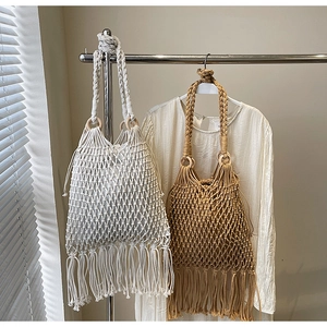 Détail du sac en paille tissé avec des pompons en coton et poignée en bois élégante