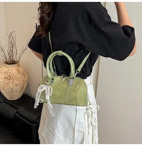 Detail der hellgrünen Boston-Handtasche mit Spitzenschleife und Perlenanhänger