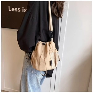 Detail view of khaki nylon bucket bag showing mesh side pocket and adjustable shoulder strap