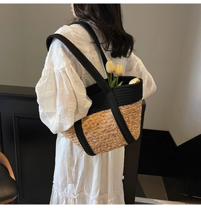 Détail d'un grand sac cabas en paille tissée avec anses en sangle noire