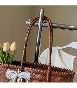 Détail du panier tressé main marron avec nœud en dentelle et perles sur l'anse