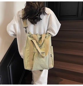 Rear view of a model wearing the light green nylon tote bag on wooden stairs