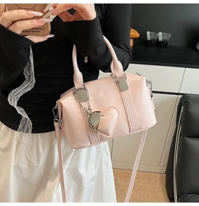 Close-up of pink glossy PU bowling bag with heart charm and adjustable strap detail