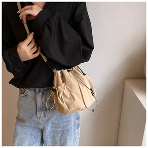 Detail of khaki drawstring bucket bag with mesh side pockets and adjustable strap