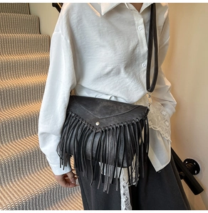 Detailed view of black PU leather crossbody bag featuring bohemian fringe and triangle flap