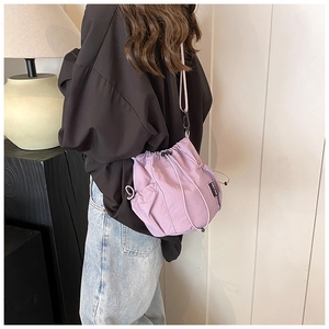 Detail of purple nylon bucket bag featuring a drawstring closure and side mesh pockets