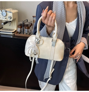 Detailansicht der cremefarbenen Tasche mit Perlen, Spitzenschleifen und Herzanhängern