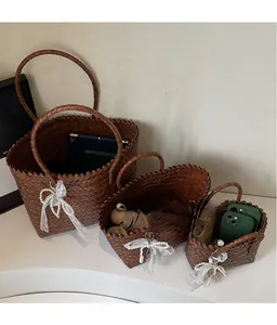 Détail de trois sacs en paille tressée de tailles variées avec breloques en dentelle