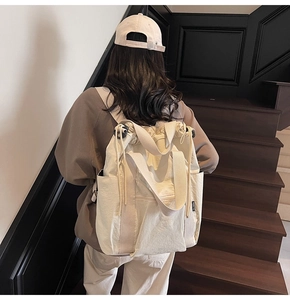 Cream canvas backpack tote with handle used as a stylish shoulder bag on a model