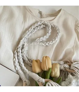 Détail de la bandoulière en coton tissé et de l'anneau en bois sur un sac en paille chic