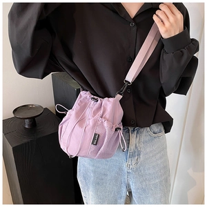 Detail of light purple nylon bucket bag featuring a drawstring closure and side mesh pocket