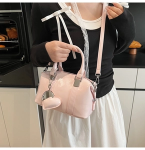 Close-up of pink patent leather handbag featuring heart charm and metallic details