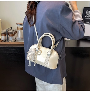 Detail der champagner-goldenen Perlmutt-Tasche mit Schleifen-Charm im schicken Cafe-Stil