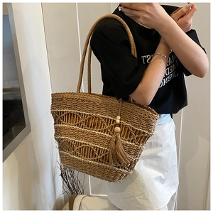Detailed close-up of woven straw tote bag with boho tassel and diamond mesh texture