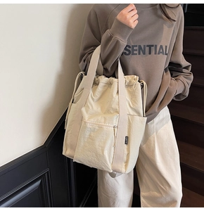 Detail of off-white nylon tote bag showing drawstring closure and side logo tag