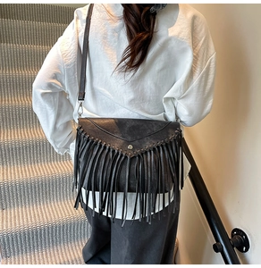 Detail einer schwarzen Leder-Umhängetasche mit modischen Fransen und Silberbeschlägen