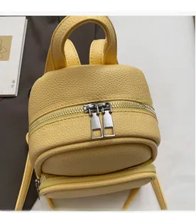 Close-up of smooth silver zippers and lychee grain leather texture on mini yellow backpack