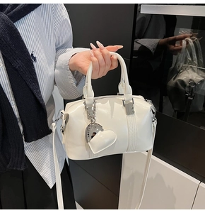Detail of white glossy mini Boston bag with heart-shaped charm and twin handles