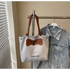 Detail of canvas tote bag showing unique bone-shaped zipper and leather handles