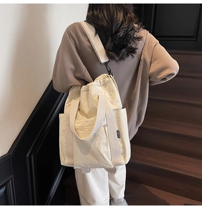 Detail view of cream white nylon tote bag with drawstring closure and brand label