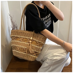 Detail of large woven straw bag with wavy texture and wooden beaded tassel charm