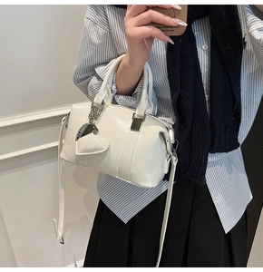 Detail of cream bowling bag featuring glossy leather texture and heart charm