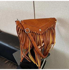 Detail of caramel vintage crossbody bag with long tassels and triangular flap lid