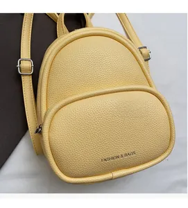 Detail of yellow mini backpack featuring litchi texture faux leather and silver metal buckles