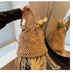 Détail d'un sac à main tissé avec poignée en bois et longues franges de glands
