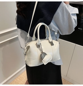 Detailed side view of off-white Boston bag with silver chain and heart charm