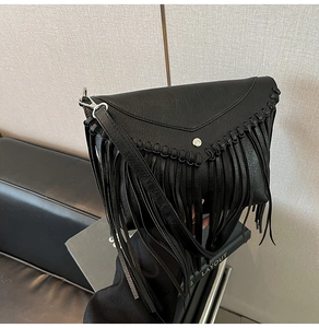 Detail of black pebbled leather crossbody bag with long tassels and woven edges