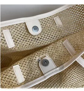 Détail du fermoir magnétique en métal sur un sac cabas en paille avec bordure en similicuir