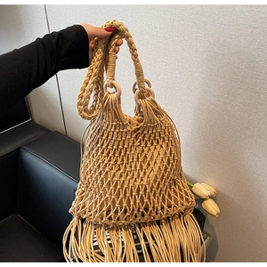 Détails d'un sac en paille tressée beige avec maille ajourée, franges et anneau en bois